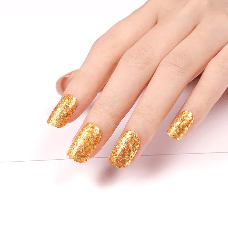 Hand wearing golden glitter nail wraps displaying shimmery metallic finish for celebration nails
