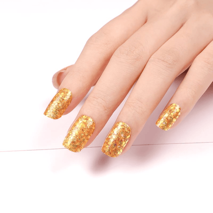 Hand wearing golden glitter nail wraps displaying shimmery metallic finish for celebration nails