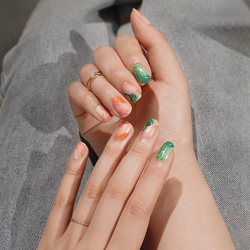Green and gold marble nail wraps on hands with elegant watercolour patterns