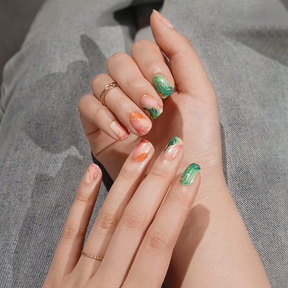 Green and gold marble nail wraps on hands with elegant watercolour patterns