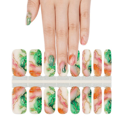 Hand selecting marble nail wraps with green orange gold foil pattern from sheet