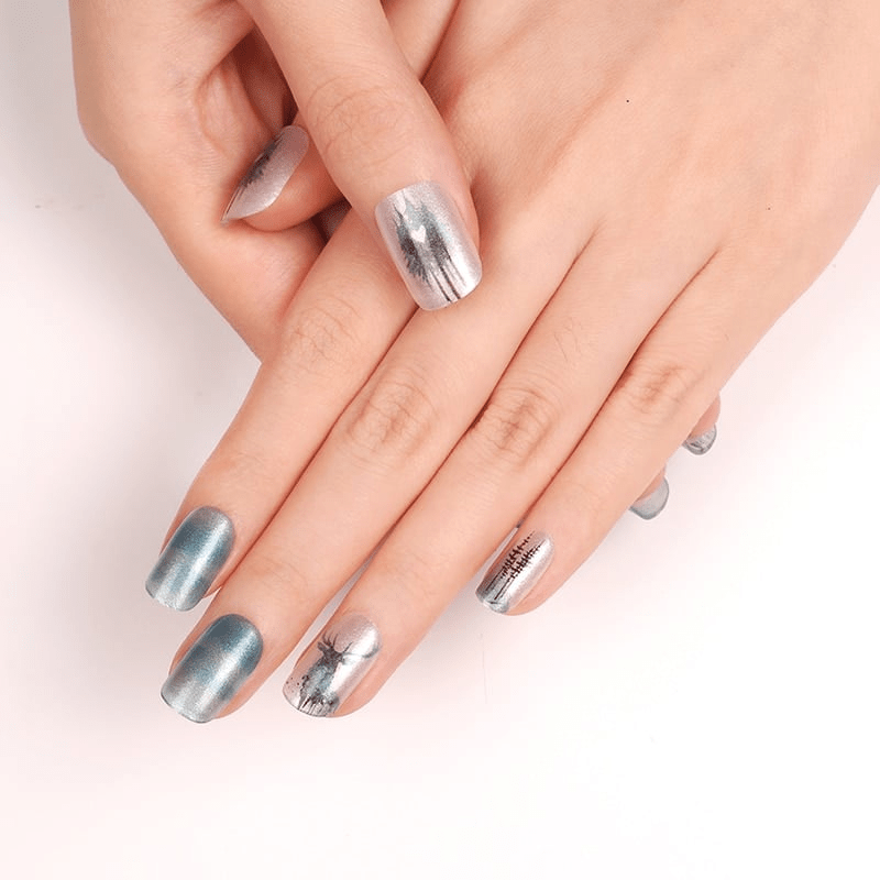 Blue-grey watercolour nail wraps on hands with woodland animal and tree patterns