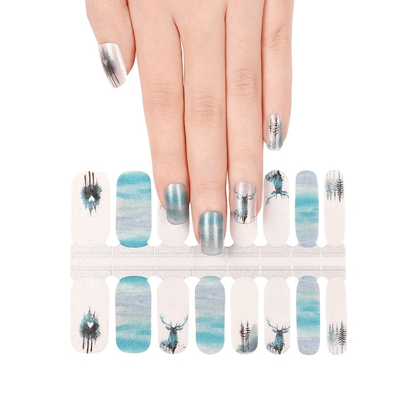 Hand wearing blue watercolour nail wraps with stag silhouettes and forest patterns
