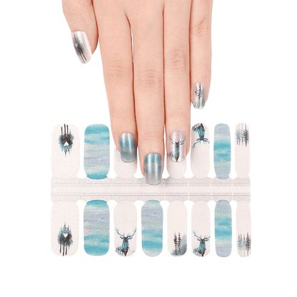 Hand wearing blue watercolour nail wraps with stag silhouettes and forest patterns