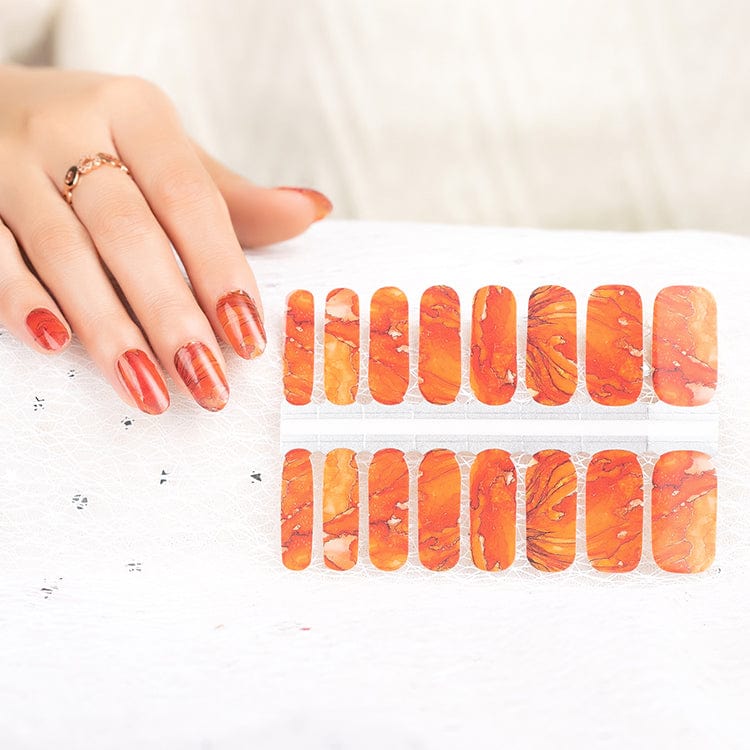 Hand displaying orange marble nail wraps with burnt terracotta gradient finish