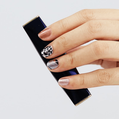 Hand displaying leopard print nail art wraps with brown caramel spots design