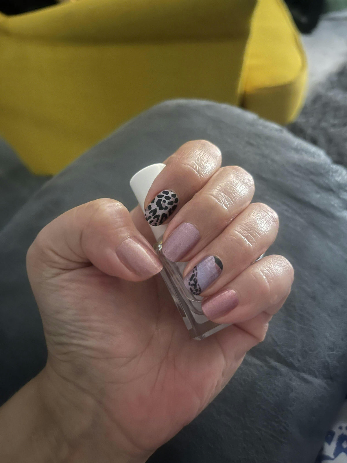 Hand wearing leopard print nail wraps in brown caramel tones with matte finish