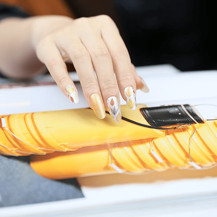 Hand with fall leaf nail art touching orange fabric autumn manicure inspiration