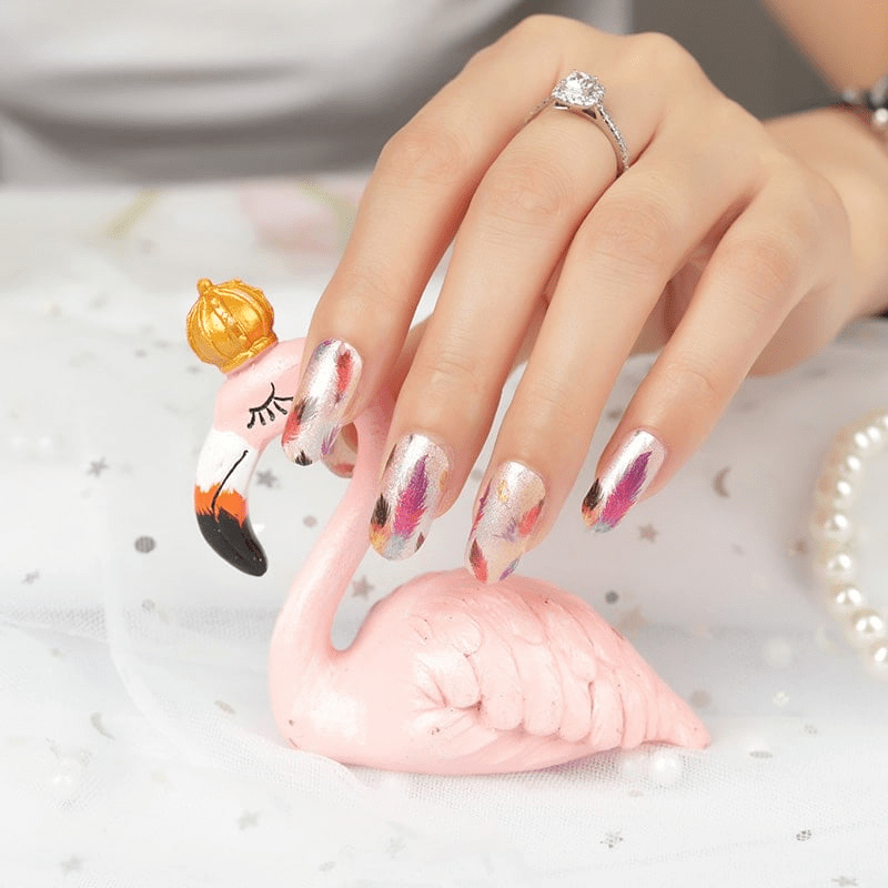 Hand wearing feather design nail wraps with pink flamingo decoration showing autumn nail art