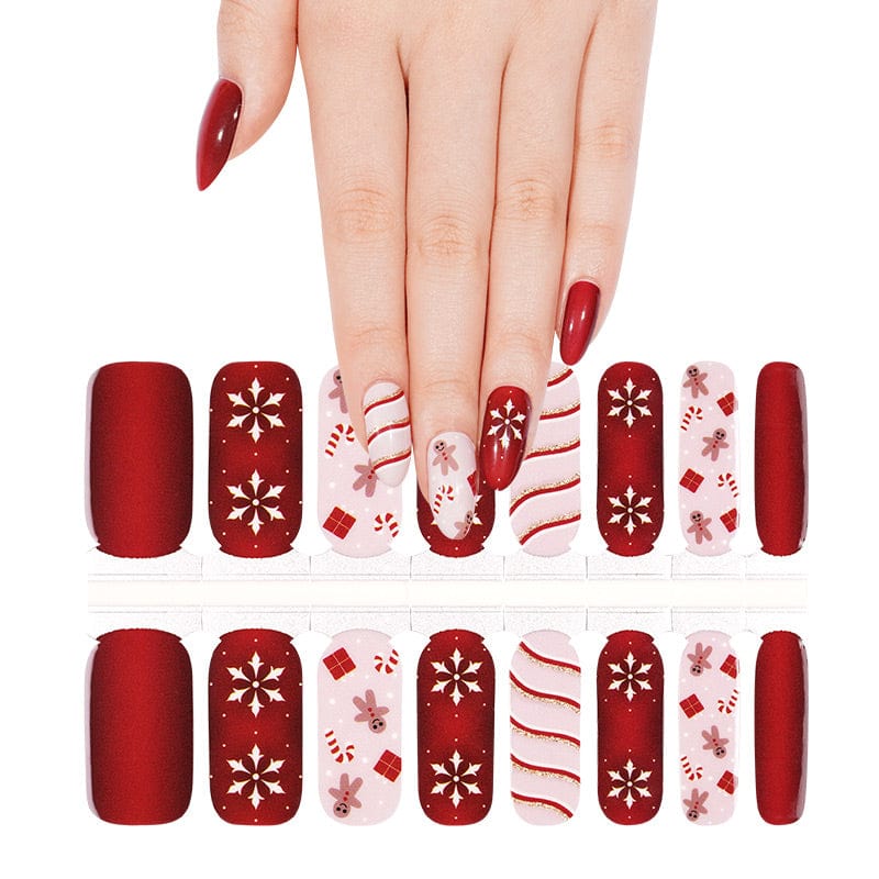 Red Christmas nail wraps with gold snowflakes and striped patterns on hand