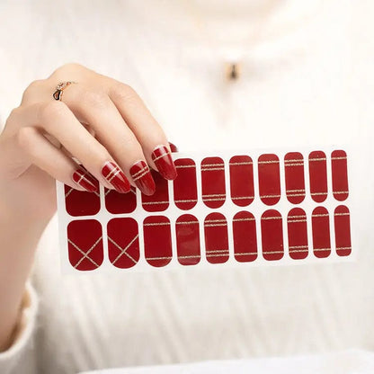 Deep red glossy nail wraps with gold glitter stripe and crisscross line accents, wide fit sheet