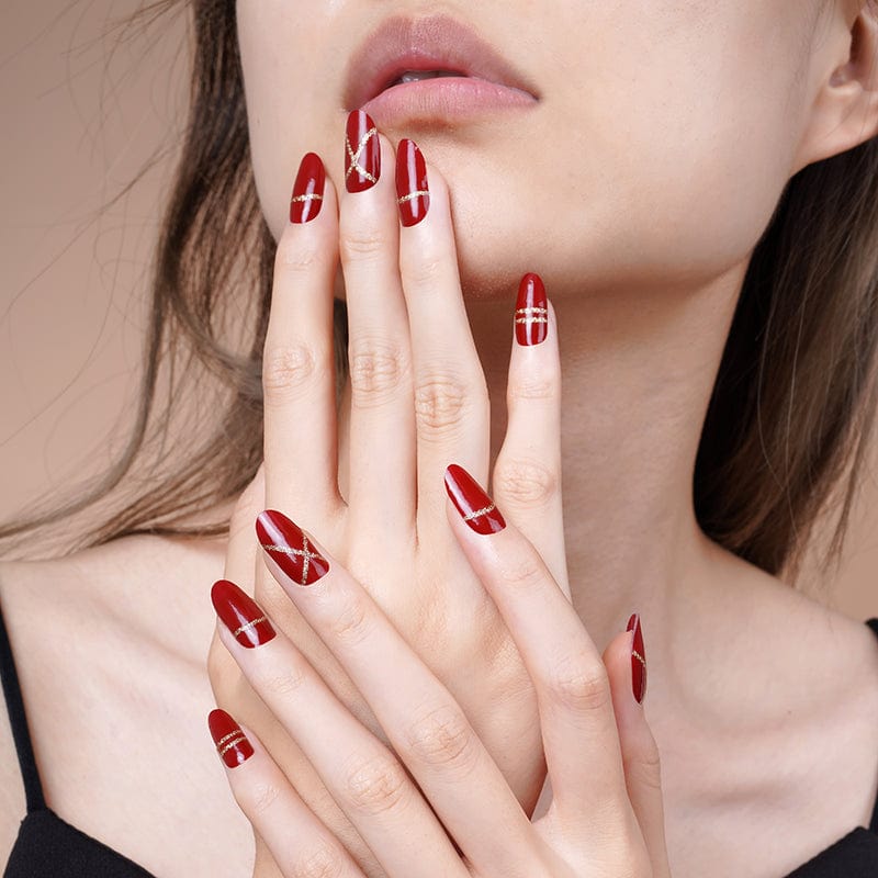 Red and gold geometric nail wraps on model hands for sophisticated party nail design