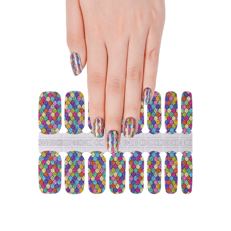 Hand applying rainbow holographic nail wraps sheet with colourful scale pattern design