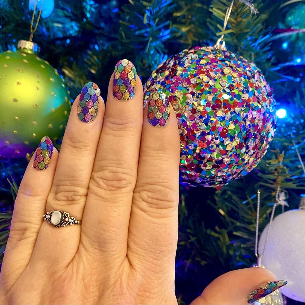 Hand wearing holographic rainbow glitter nail wraps with multicoloured sparkles and Christmas baubles