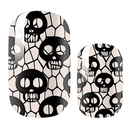 Nail wraps with black skulls on a cream crackled fishnet pattern, glow-in-the-dark finish