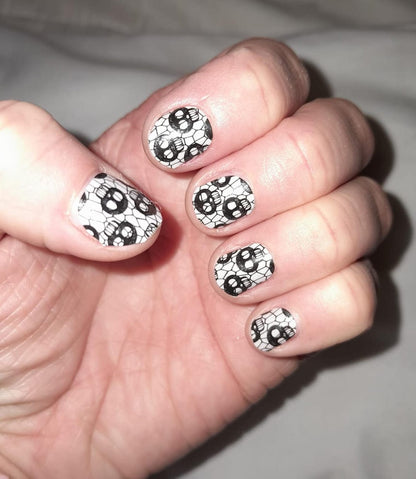 Black and white skull pattern nail wraps applied on hand showing gothic nail art
