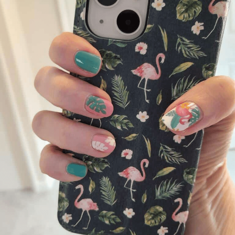 Hand holding phone showing tropical flamingo nail wraps with teal and pink nail art