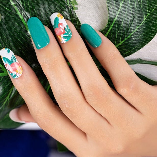 Hand with green tropical nail art featuring flamingo and botanical leaf nail wrap designs