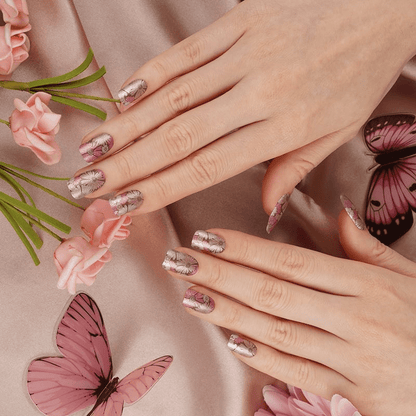 Pink floral nail wraps with pressed flower pattern on hands with butterfly decorations