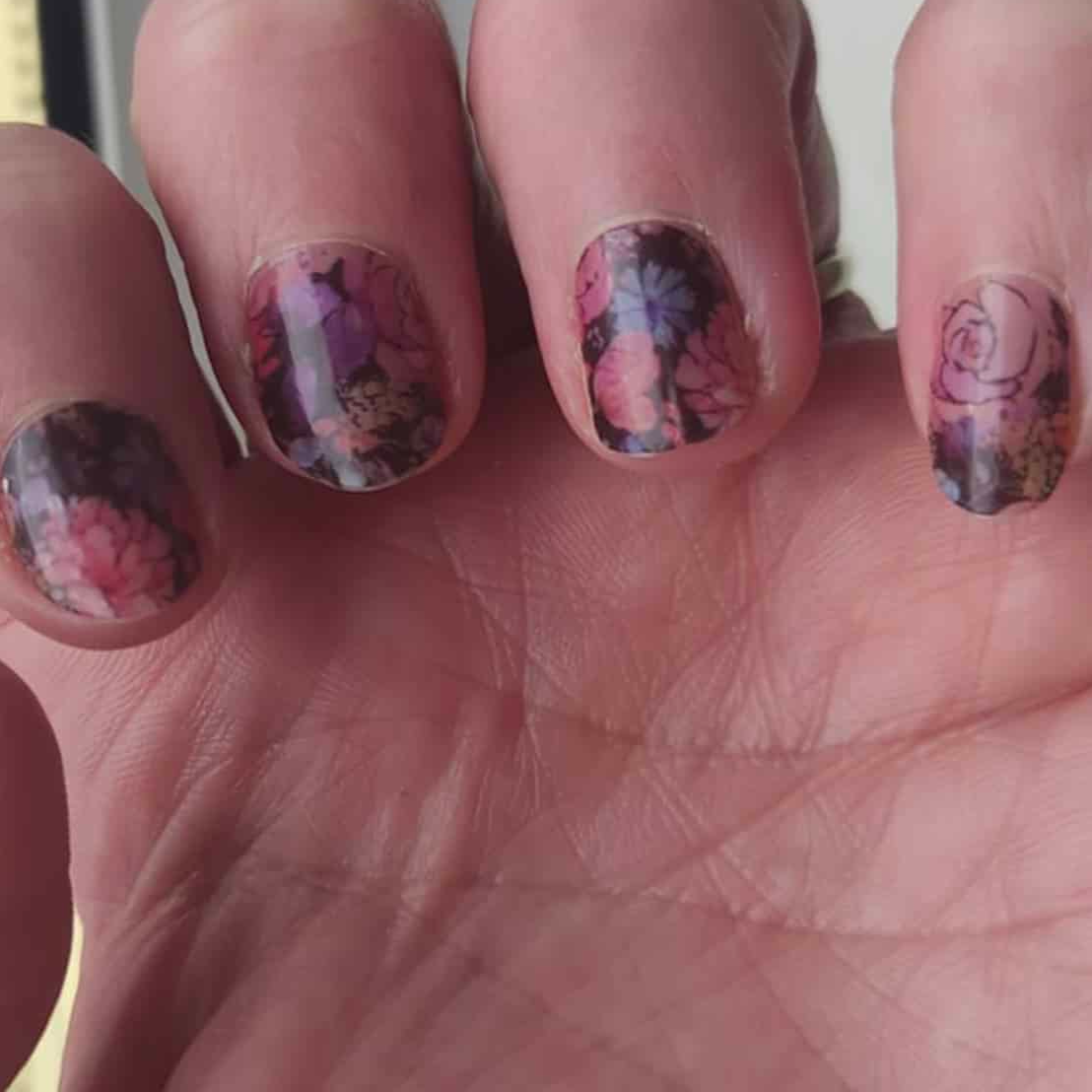 Dark floral nail art wraps applied on fingernails with romantic rose pattern