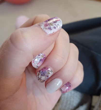 Close-up of watercolour floral nail wraps on fingers featuring pink roses and botanical patterns