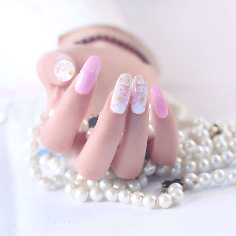 Pink floral nail wraps with white daisy pattern on hand with pearl accessories