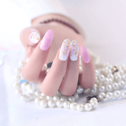 Pink floral nail wraps with white daisy pattern on hand with pearl accessories