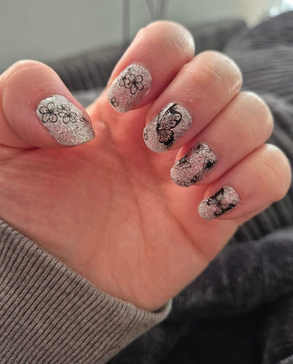 Silver glitter nail wraps with black butterfly and floral line-art accents