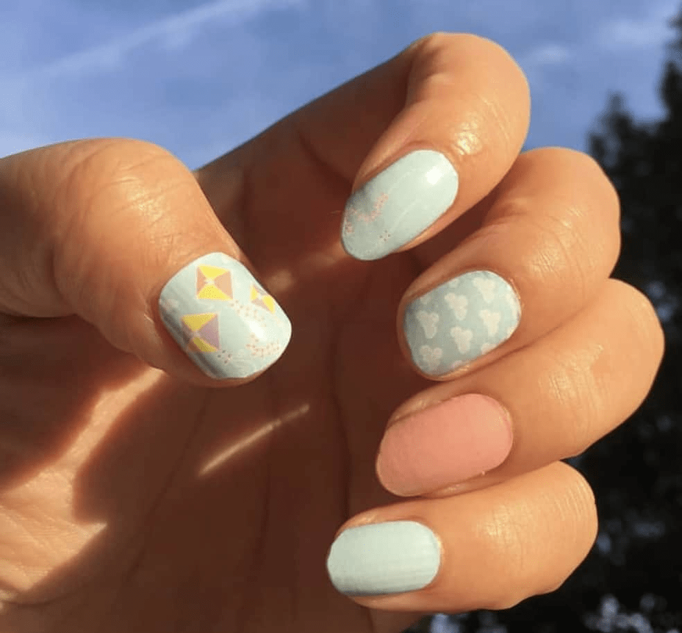 Sky blue nail wraps with yellow kite patterns applied on hand showing whimsical nail art design