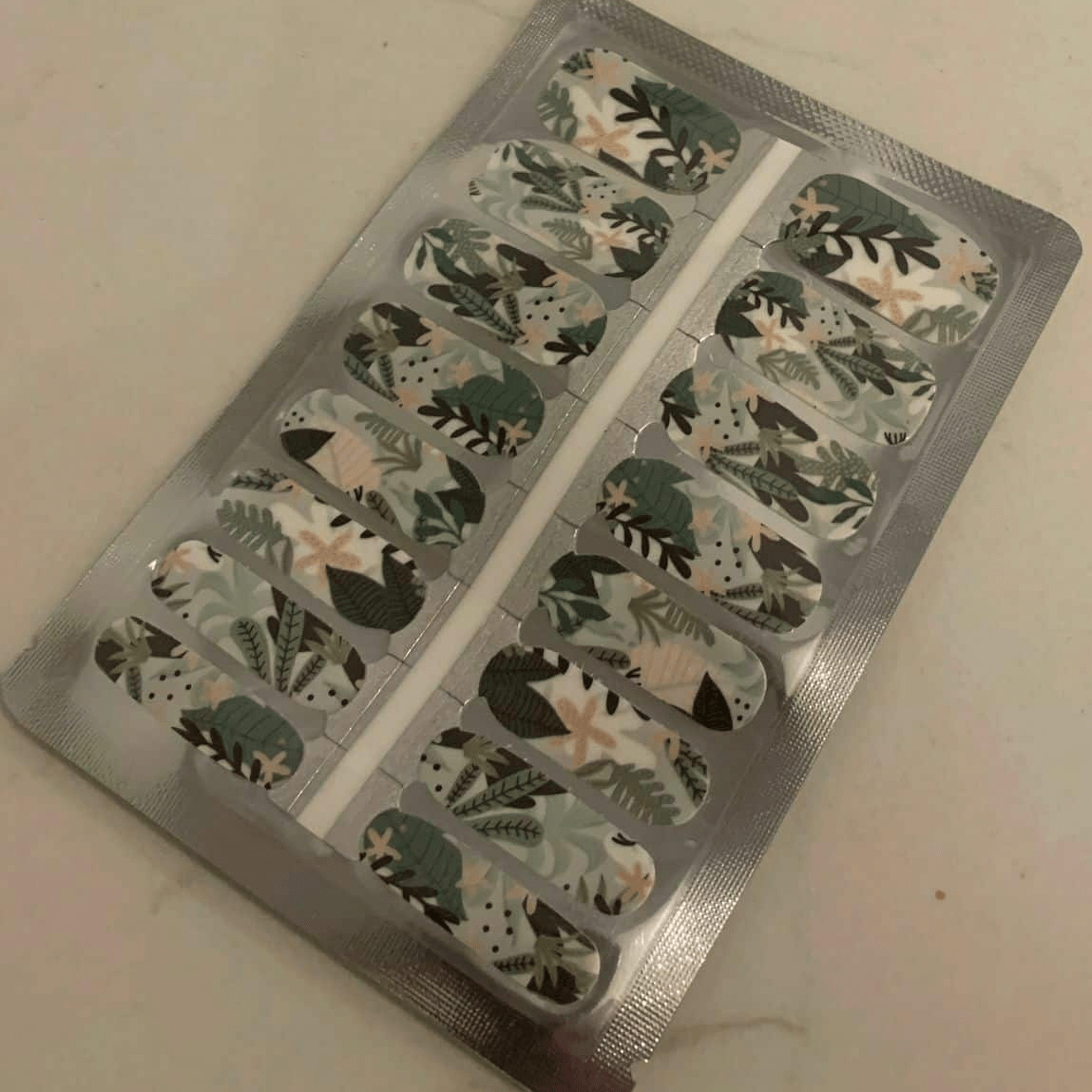 Nail wraps with green and cream tropical leaf print on white, botanical design