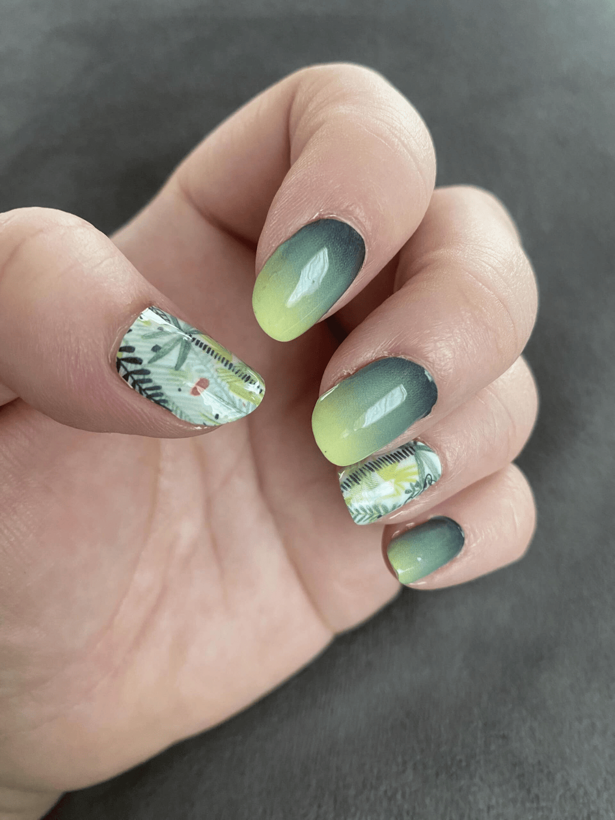 Green ombre gradient nail wraps with botanical leaf patterns on hand manicure