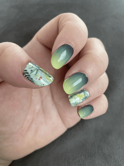 Green ombre gradient nail wraps with botanical leaf patterns on hand manicure