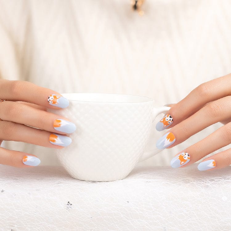 Grey and orange fox nail art wraps on hands holding white mug