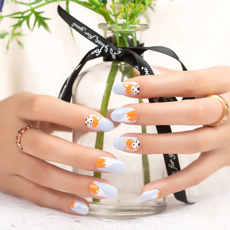 Hands wearing cute fox nail art wraps with orange cartoon foxes on grey base