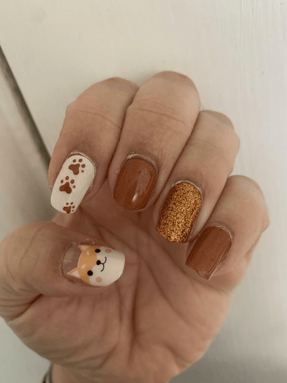 Brown and orange fox nail wraps with glitter accent on hand manicure