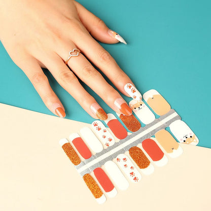 Hand wearing fox-themed nail wraps with orange, brown, glitter and cute fox designs on turquoise background