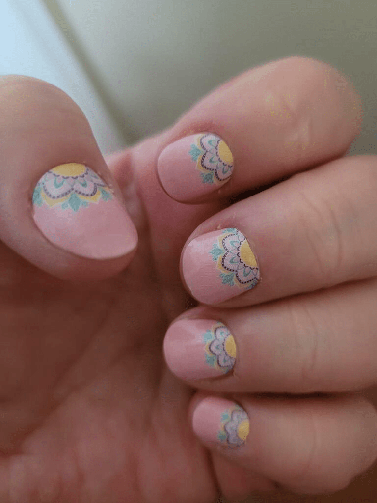 Pink nail wraps with pastel mandala floral design in yellow, teal and lilac at base