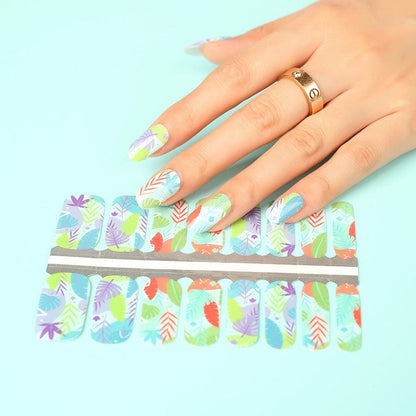 Hand applying botanical nail wraps with tropical leaf pattern in multicoloured design sheet