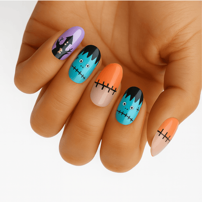 Halloween nail wraps on hand featuring Frankenstein faces, haunted houses, and stitched patterns in turquoise and purple