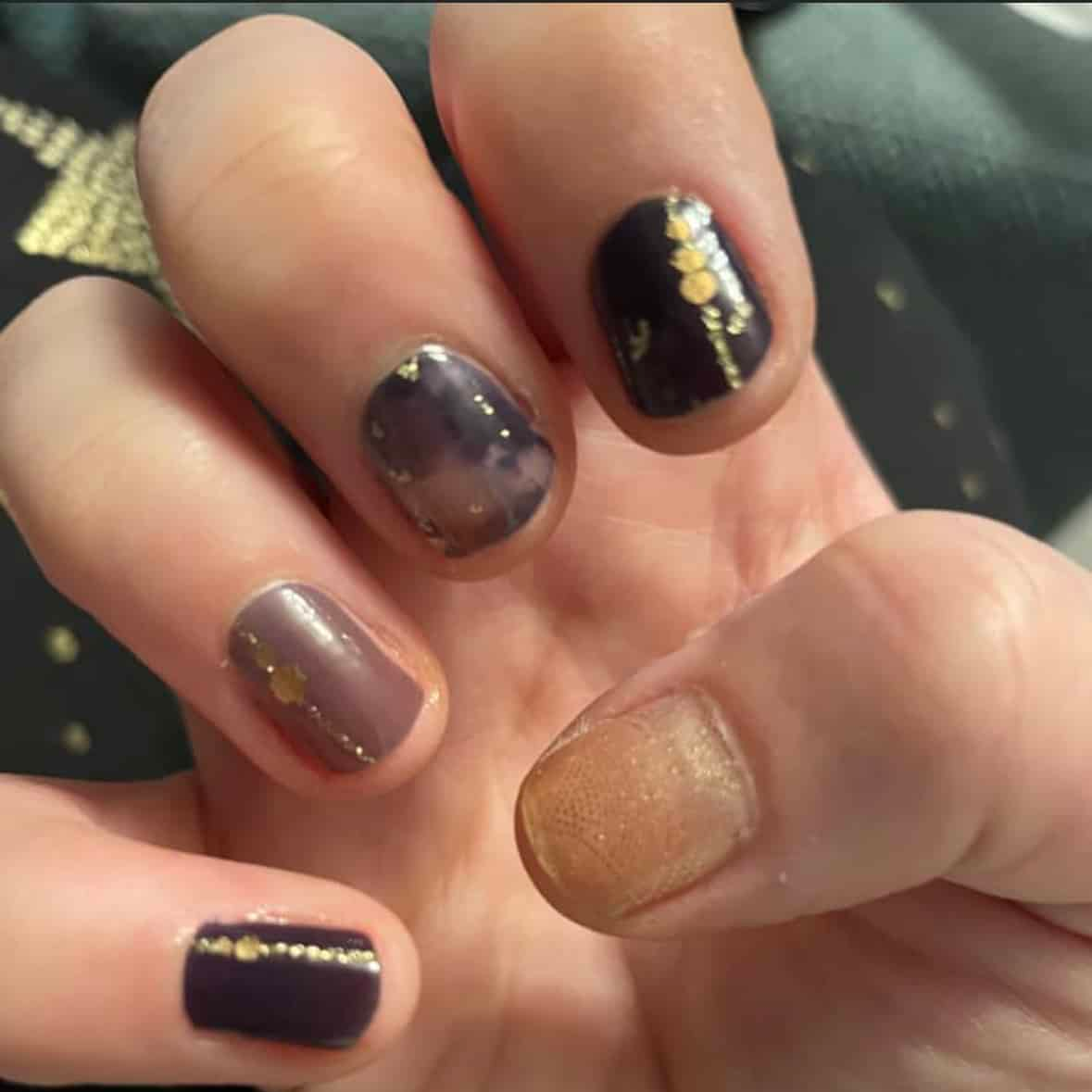 Hand wearing marble effect nail wraps in grey brown and gold metallic foil finish