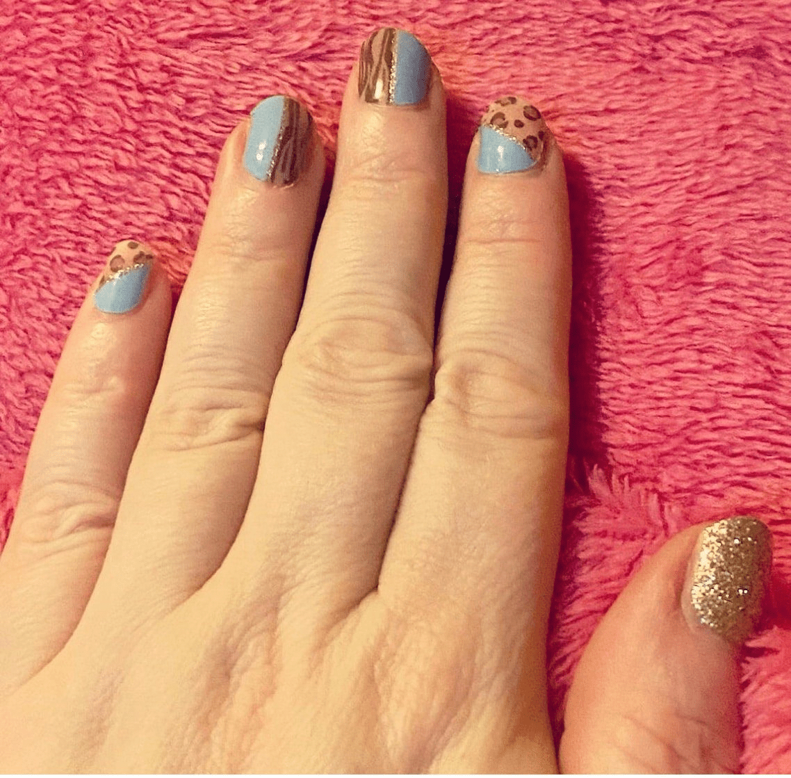Blue and gold nail wraps with leopard print pattern on hand manicure