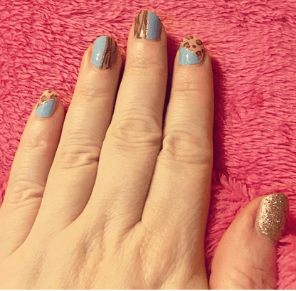 Blue and gold nail wraps with leopard print pattern on hand manicure