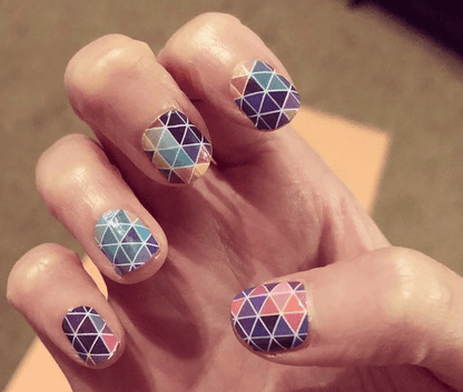 Geometric nail art wraps on hand featuring triangle mosaic in purple gradient