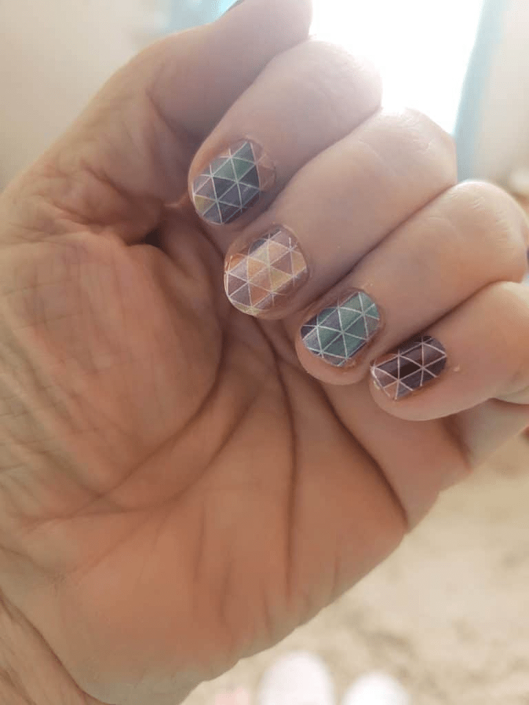 Triangle geometric nail wraps on hand showing multicoloured mosaic pattern design