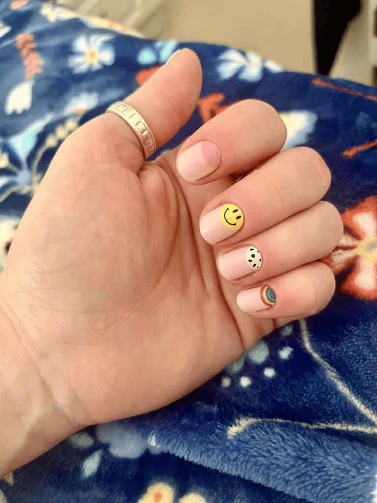 Hand wearing retro nail wraps with yellow smiley face and black white patterns