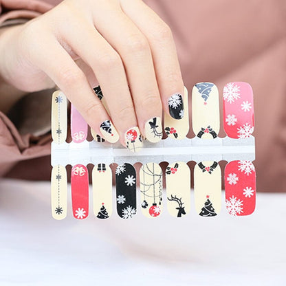 Christmas nail wraps on hand showing festive baubles, snowflakes and reindeer designs in red black cream