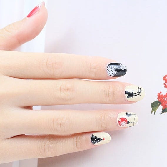 Festive nail art wraps on hand featuring Christmas baubles, reindeer and snowflake designs for holiday manicure