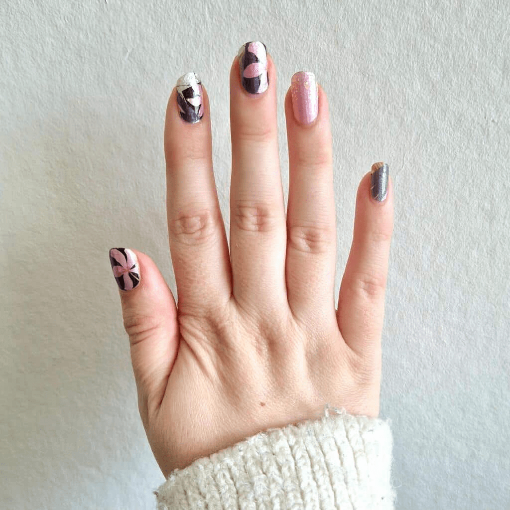 Hand wearing pink and grey floral nail wraps with botanical leaf pattern