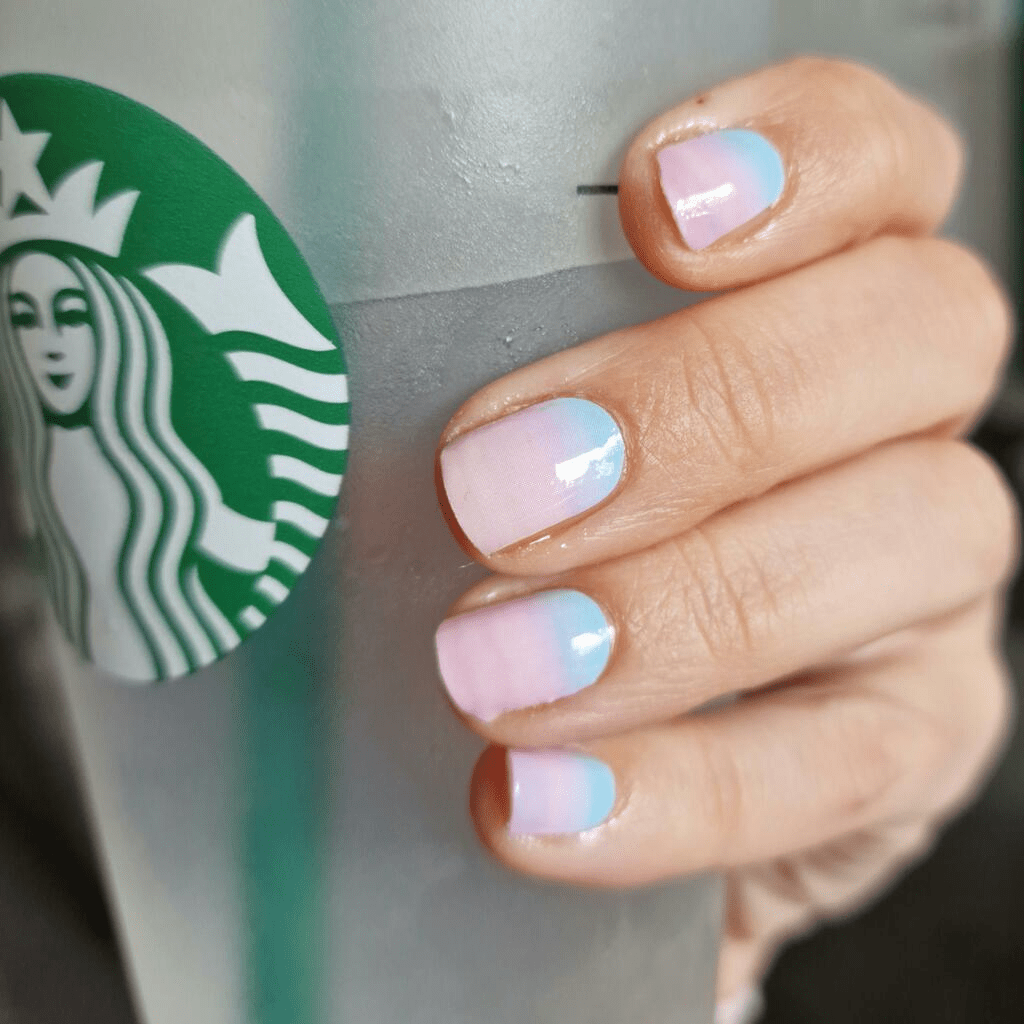 Hand holding coffee cup showing pink blue ombre nail wraps gradient manicure
