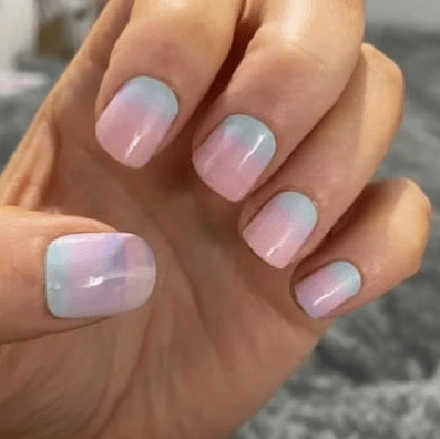 Close-up hands displaying pastel pink blue gradient nail wraps ombre design